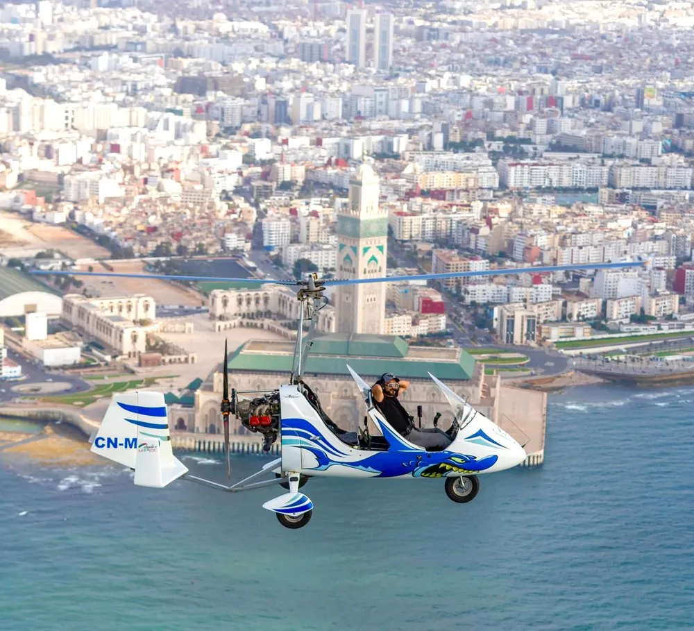 Gyrocoptère en vol devant une mosquée, au-dessus de la mer