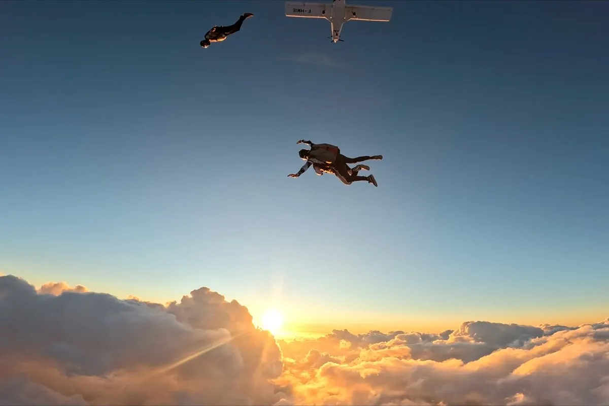 Saut en parachute en tandem au coucher du soleil au-dessus des nuages