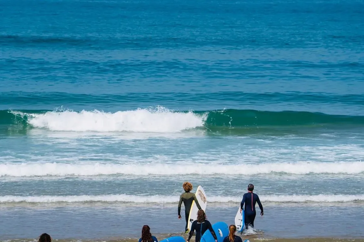 Surfeurs débutants entrant dans l'eau avec leurs planches